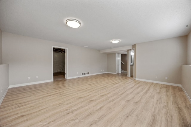 unfurnished room with visible vents, baseboards, light wood finished floors, and a textured ceiling