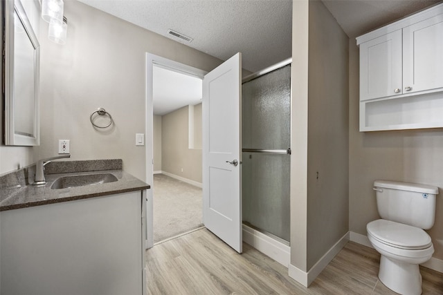 full bath featuring wood finished floors, visible vents, baseboards, a shower stall, and toilet