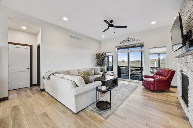 living area featuring visible vents, a ceiling fan, recessed lighting, a stone fireplace, and light wood finished floors