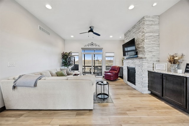 living room featuring a ceiling fan, visible vents, a fireplace, recessed lighting, and light wood-style floors