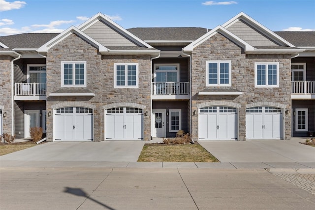 townhome / multi-family property featuring stone siding, an attached garage, and concrete driveway