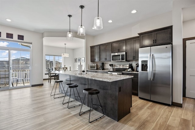 kitchen featuring a breakfast bar, dark brown cabinets, light wood-type flooring, and appliances with stainless steel finishes