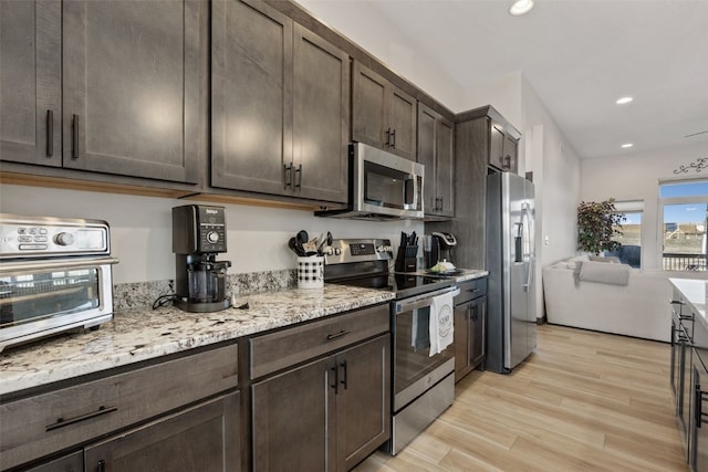 kitchen featuring light stone counters, light wood-style flooring, recessed lighting, stainless steel appliances, and dark brown cabinetry