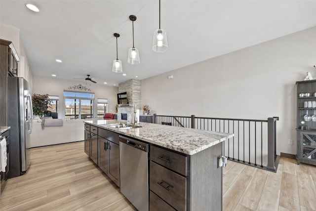 kitchen featuring a stone fireplace, ceiling fan, dark brown cabinets, and stainless steel appliances