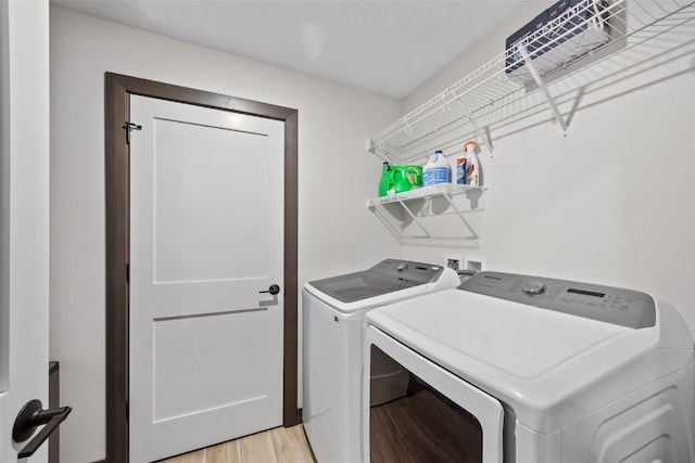 washroom featuring laundry area, light wood-style flooring, and washer and clothes dryer