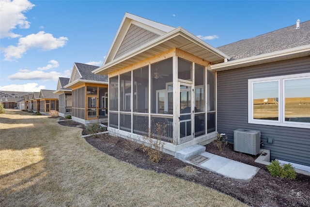 rear view of house featuring cooling unit, a yard, and a sunroom