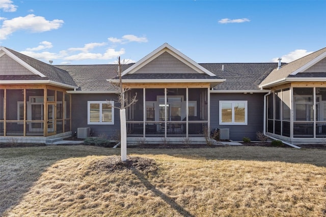 rear view of house featuring central AC, a shingled roof, a yard, and a sunroom