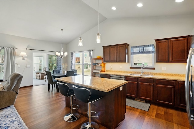 kitchen featuring dark wood-type flooring, a sink, open floor plan, a center island, and a breakfast bar area