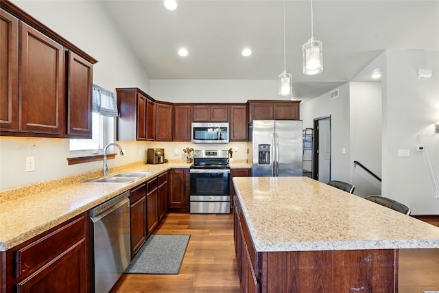 kitchen featuring dark wood-type flooring, a sink, a kitchen island, stainless steel appliances, and light countertops