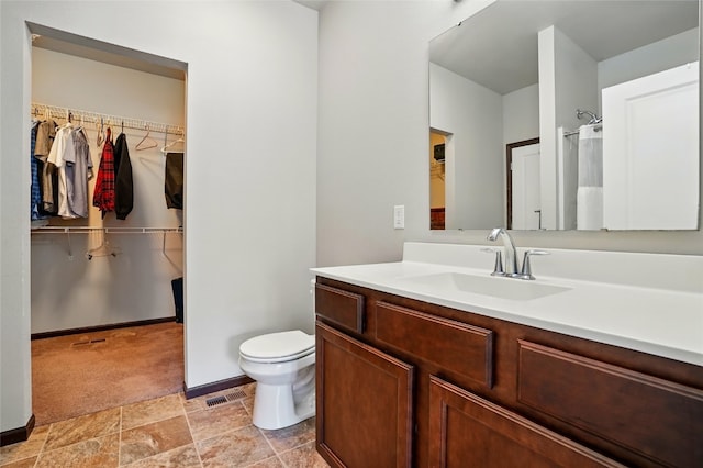 full bath with vanity, a shower with curtain, visible vents, a walk in closet, and toilet