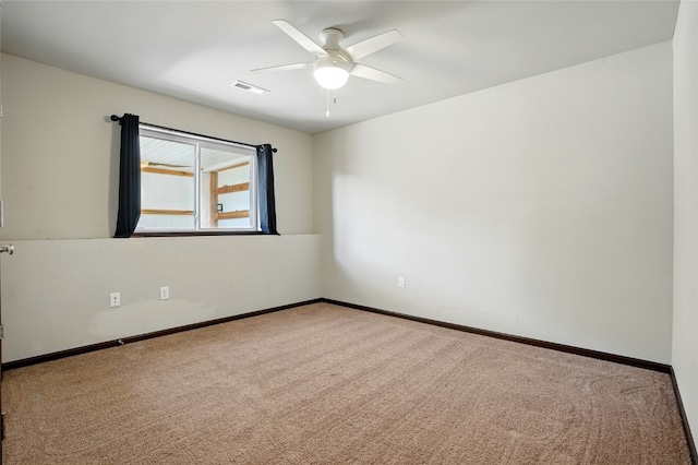 carpeted spare room featuring visible vents, baseboards, and ceiling fan