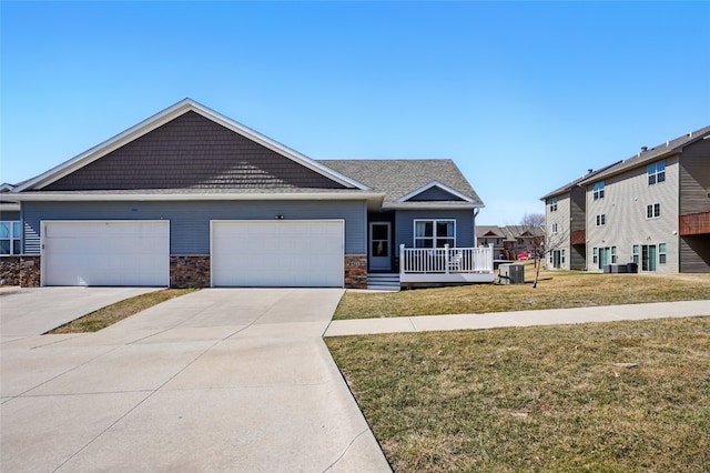 craftsman house with a front yard, central AC unit, an attached garage, concrete driveway, and stone siding