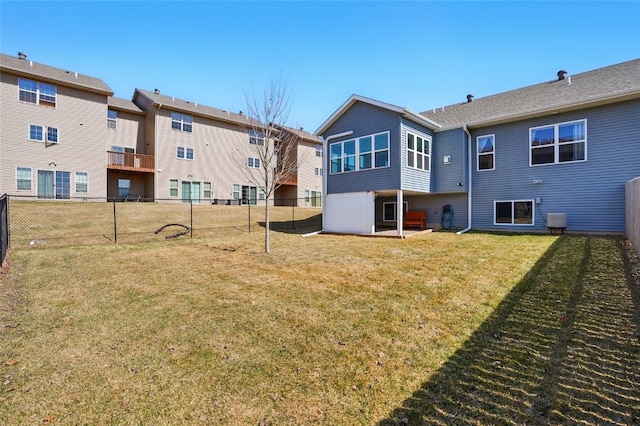 rear view of property featuring a yard and fence