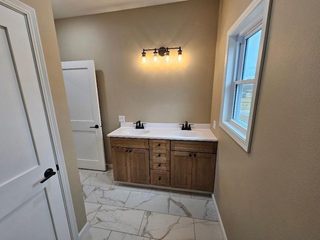 bathroom with double vanity, marble finish floor, baseboards, and a sink