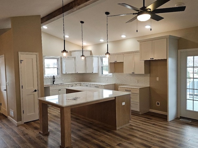 kitchen featuring a sink, lofted ceiling with beams, dark wood-style floors, and a kitchen island