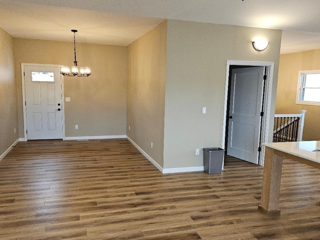 unfurnished dining area with baseboards, dark wood-type flooring, and an inviting chandelier