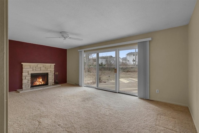 unfurnished living room with baseboards, carpet flooring, a fireplace, a textured ceiling, and a ceiling fan