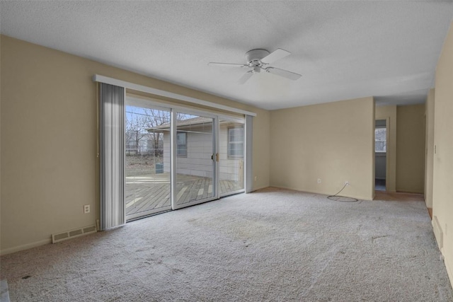 carpeted empty room featuring a textured ceiling, visible vents, and ceiling fan