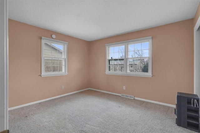 carpeted empty room featuring baseboards and visible vents