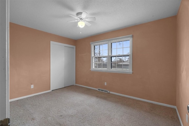 unfurnished bedroom featuring visible vents, a textured ceiling, a closet, carpet, and baseboards