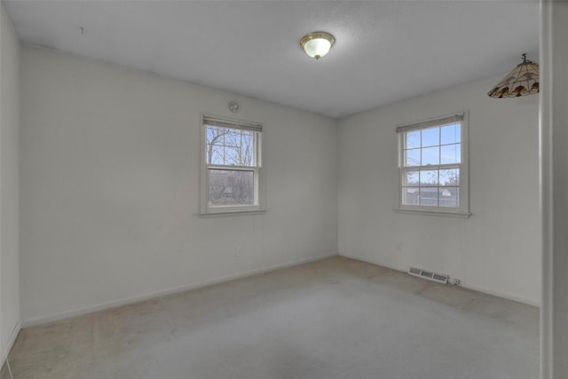 carpeted spare room featuring baseboards and visible vents