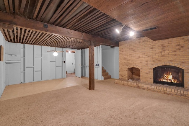 finished basement with stairs, visible vents, a fireplace, and carpet flooring