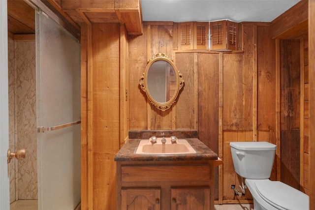 half bathroom featuring wood walls, toilet, and vanity