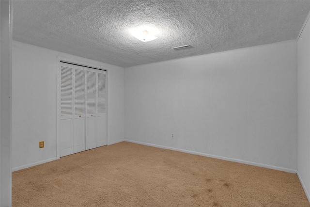 unfurnished bedroom featuring carpet flooring, baseboards, a closet, and a textured ceiling