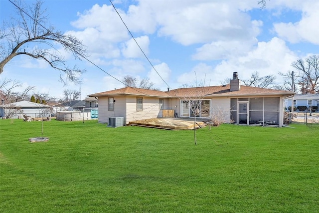 rear view of property featuring a yard, central AC unit, a sunroom, and a wooden deck