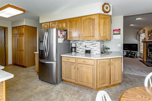 kitchen featuring backsplash, brown cabinets, light countertops, and stainless steel refrigerator with ice dispenser