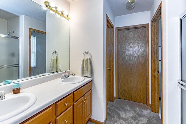 bathroom with double vanity, a shower with door, and a sink