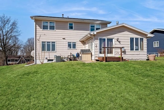 rear view of house featuring cooling unit and a lawn