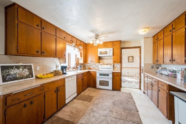 kitchen with decorative backsplash, white appliances, brown cabinetry, and light countertops