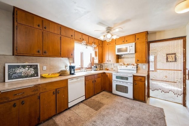 kitchen with white appliances, light countertops, brown cabinets, and backsplash