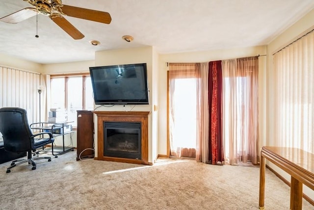 carpeted office with a glass covered fireplace, plenty of natural light, and a ceiling fan