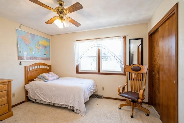 bedroom featuring visible vents, a ceiling fan, a closet, baseboards, and light colored carpet