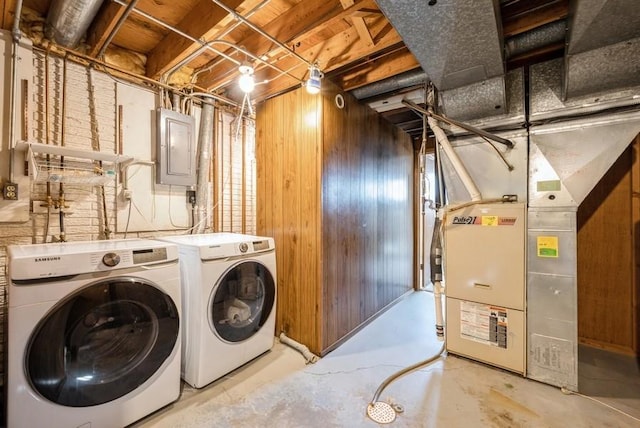 washroom featuring wooden walls, washer and clothes dryer, electric panel, laundry area, and heating unit