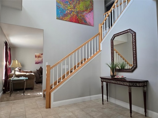 stairway featuring a high ceiling and baseboards