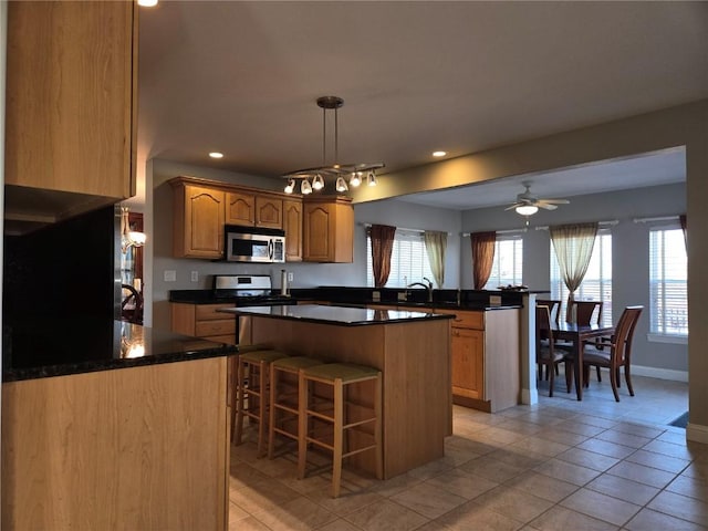 kitchen featuring a ceiling fan, stainless steel microwave, a center island, a peninsula, and range