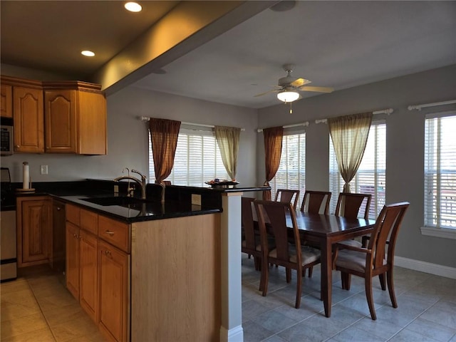 kitchen with a ceiling fan, a peninsula, a healthy amount of sunlight, and a sink