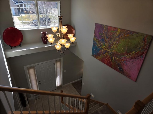 foyer entrance with a chandelier, stairs, and baseboards