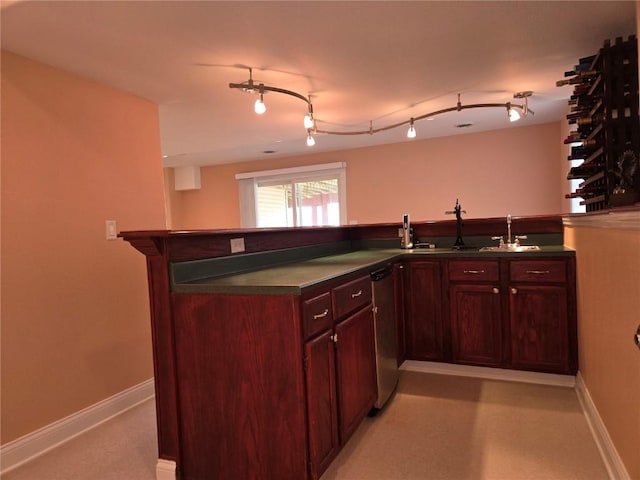 kitchen with reddish brown cabinets, baseboards, dark countertops, and stainless steel dishwasher