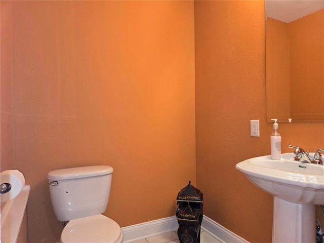 bathroom with toilet, a sink, tile patterned flooring, baseboards, and a bath