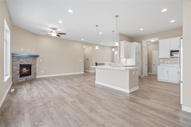 kitchen featuring open floor plan, baseboards, light wood-type flooring, and ceiling fan