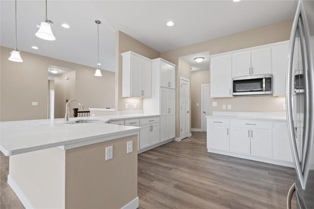 kitchen featuring wood finished floors, white cabinetry, stainless steel appliances, and a sink