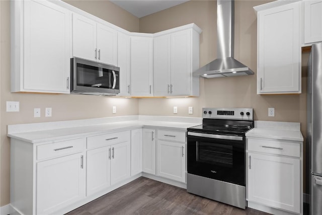 kitchen with wall chimney range hood, light countertops, dark wood-style floors, white cabinets, and stainless steel appliances