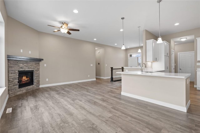 kitchen with light countertops, white cabinets, a ceiling fan, and light wood-style floors