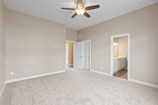 unfurnished bedroom featuring a ceiling fan, visible vents, baseboards, ensuite bathroom, and light carpet