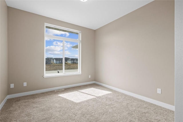 carpeted spare room featuring baseboards