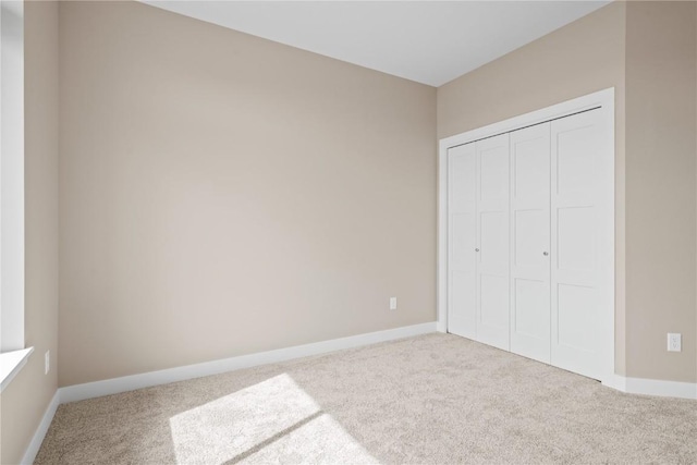 unfurnished bedroom featuring a closet, baseboards, and carpet floors